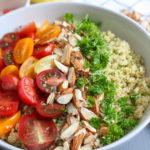 Bowl of quinoa salad with parsley, almonds, and tricolor grape tomatoes