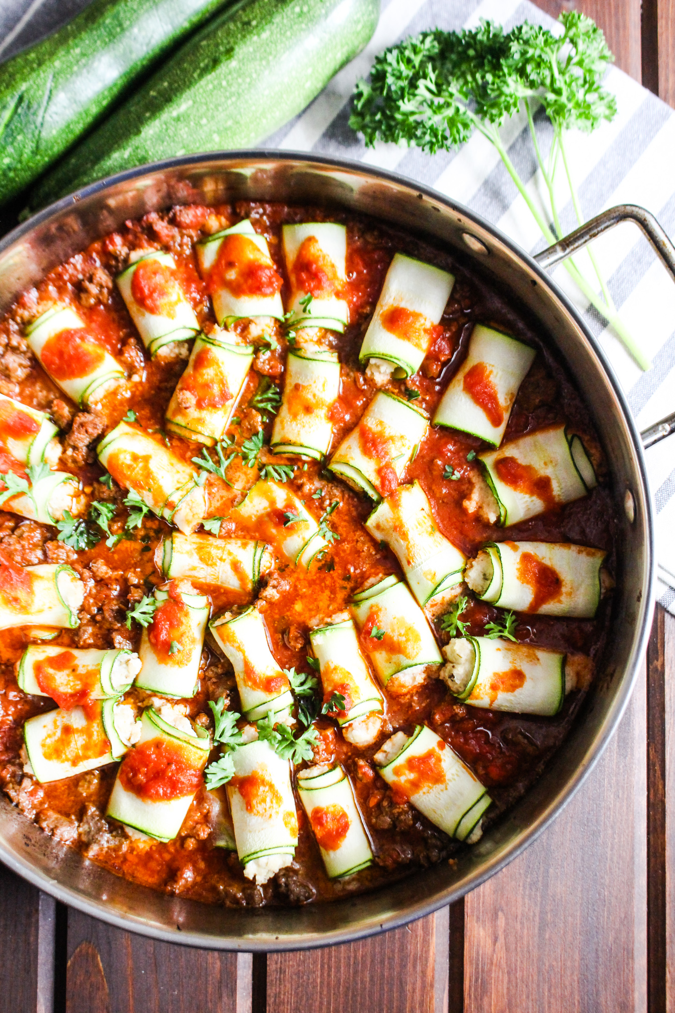 Zucchini Rollatini in a skillet with dairy-free macadamia ricotta and red meat sauce.