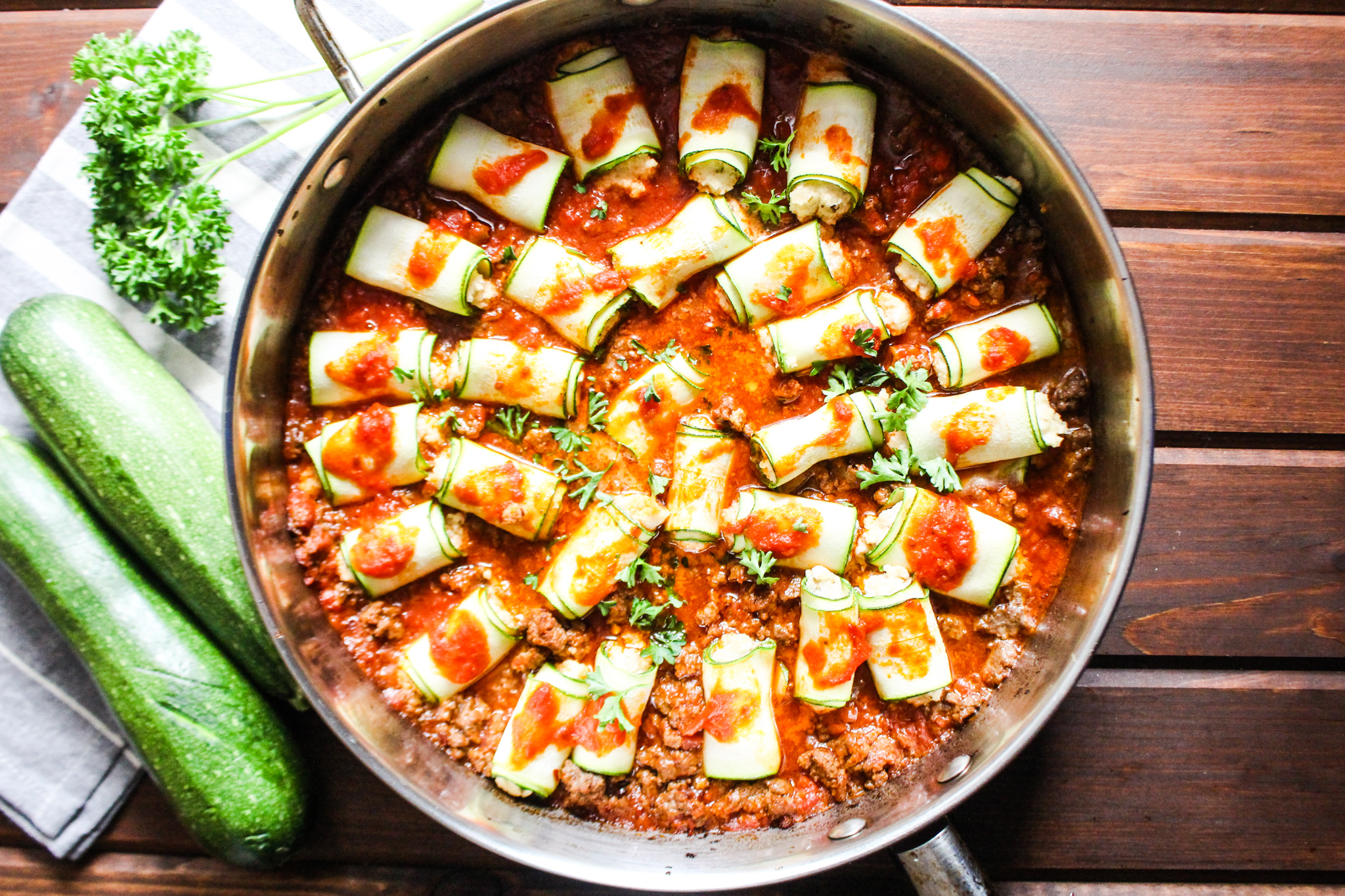 Photo of skillet with zucchini rollatini in red meat sauce. 