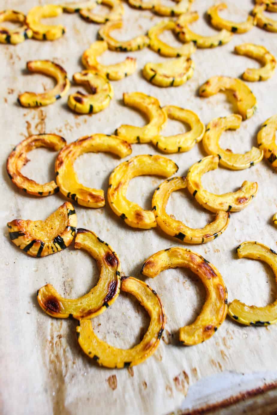 roasted deelicata squash half moons on baking sheet