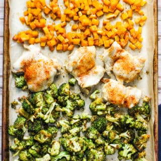 Sheet pan with cooked cubed butternut squash, four chicken thighs, and broccoli