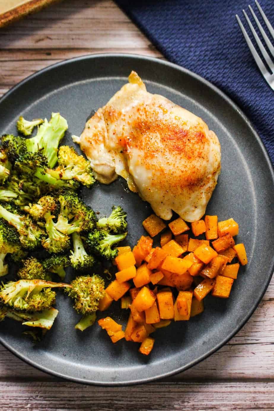 Sheet pan chicken thighs with roasted broccoli and butternut squash on a plate