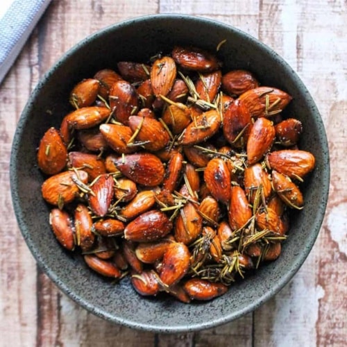 A bowl of rosemary almonds on the table.