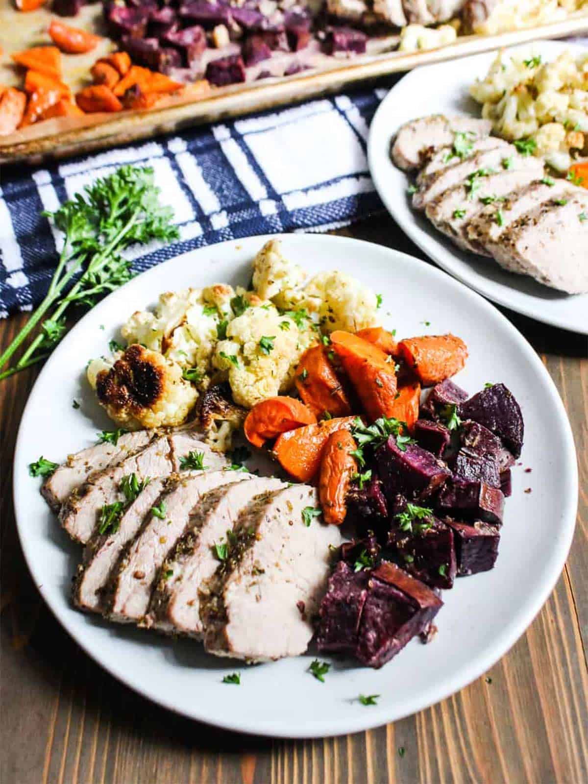 Sheet pan pork tenderloin served up on a plate with vegetables.