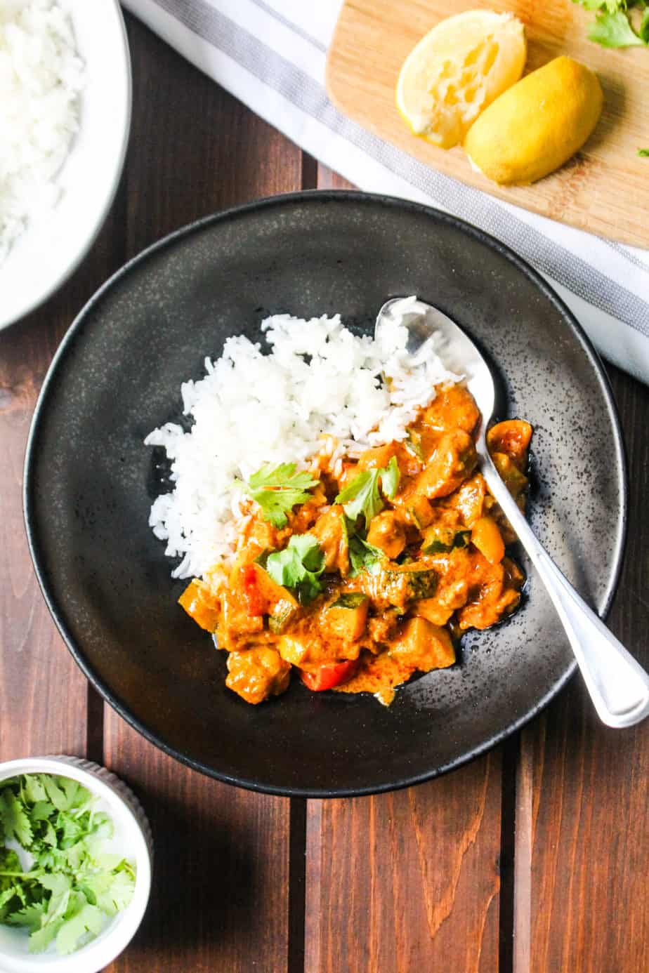 black bowl with white rice and butter chicken and vegetables