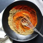black bowl with colorful spices being stirred with a whisk