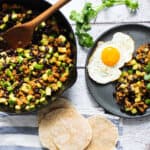 display of tortillas, cilantro, a plate with a sunny side up egg and a skillet with chorizo zucchini black beans