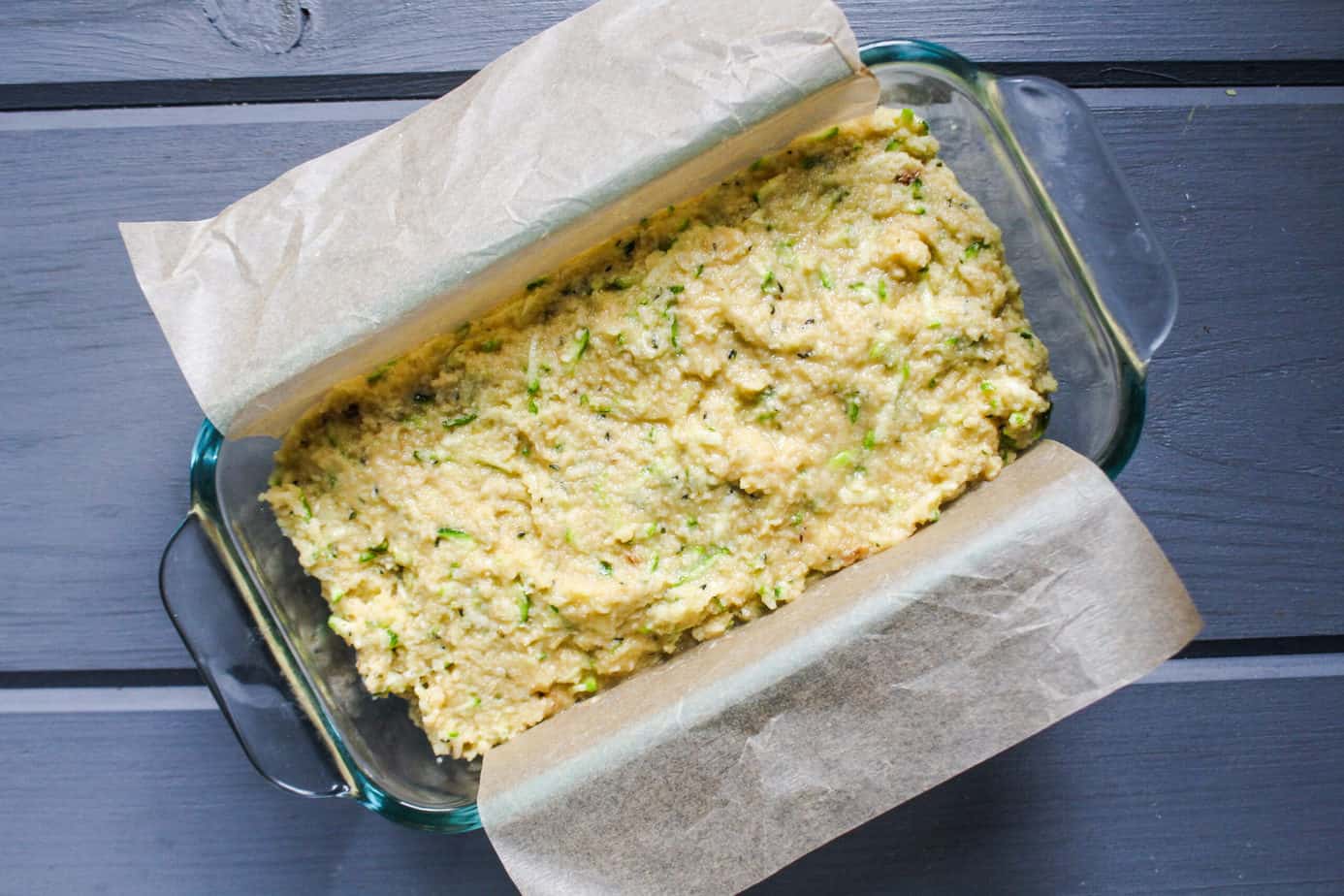 raw zucchini bread batter in bread pan with parchment paper