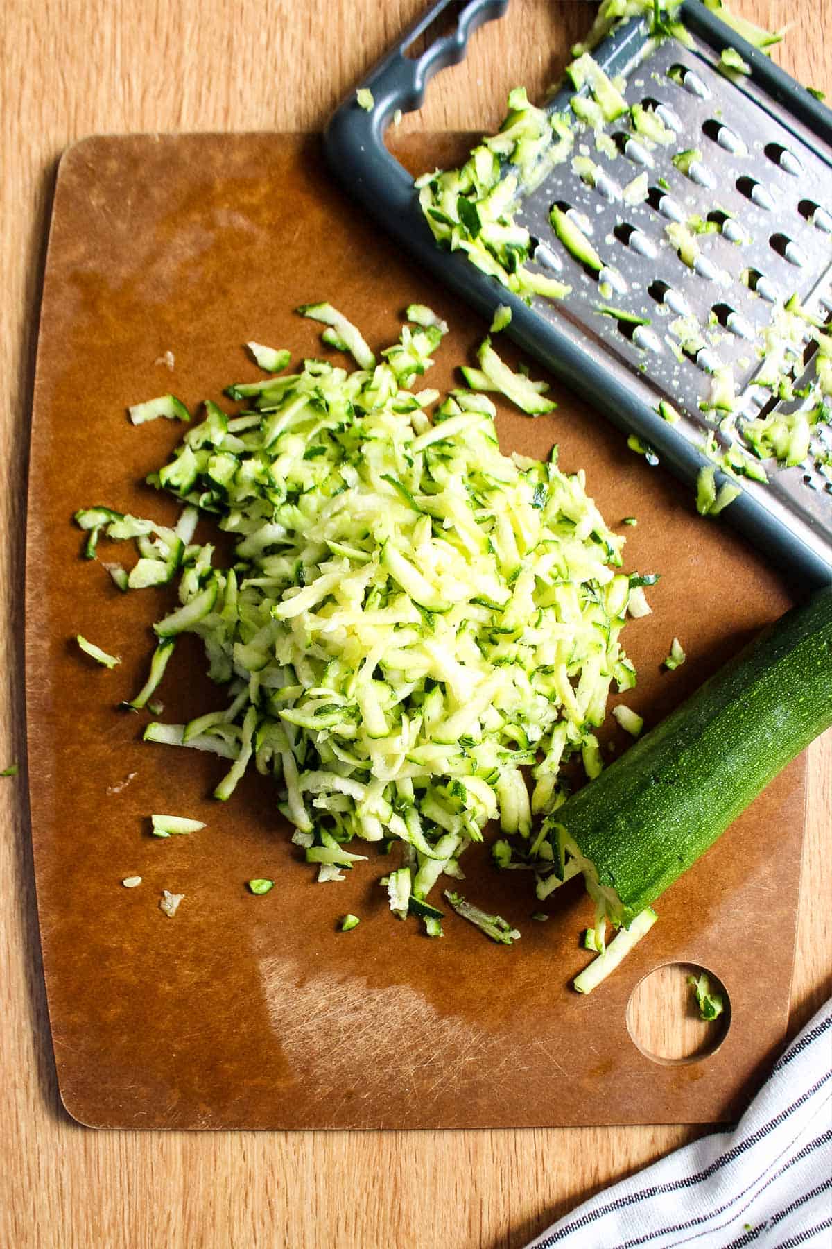 Grated zucchini on a cutting board to make low sugar zucchini bread.