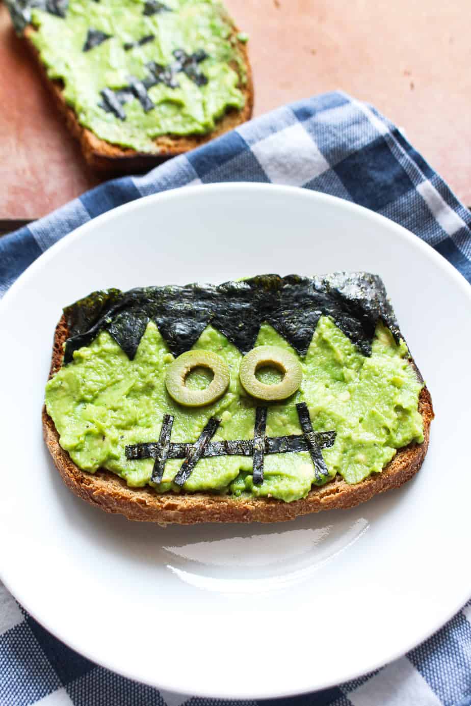 avocado toast decorated with nori and olives to look like frankenstein