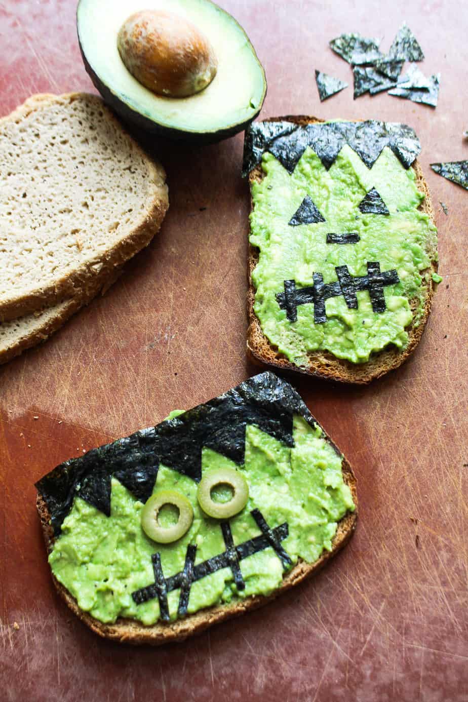 avocado toast decorated with nori and olives to look like frankenstein