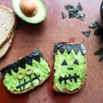 avocado toast decorated with nori and olives to look like frankenstein