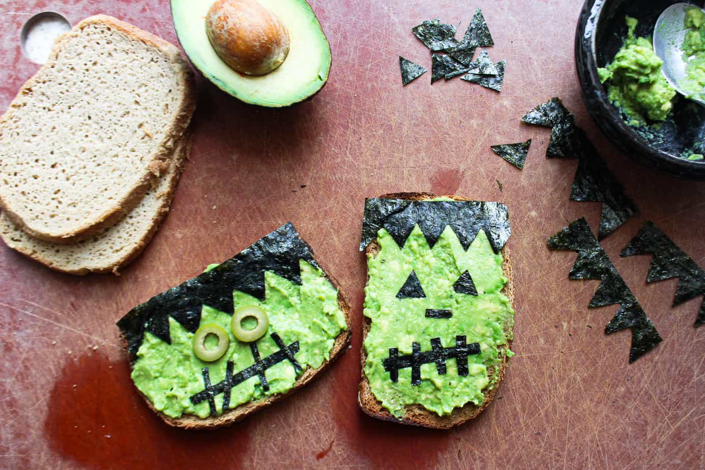 avocado toast decorated with nori and olives to look like frankenstein