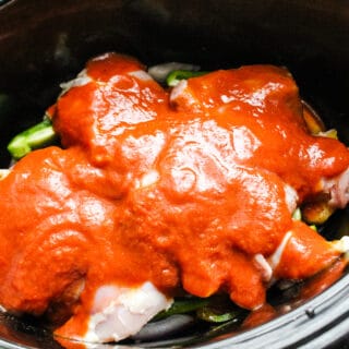 Slow cooker with pineapple, vegetables, white beans, and chicken thighs, topped with BBQ sauce