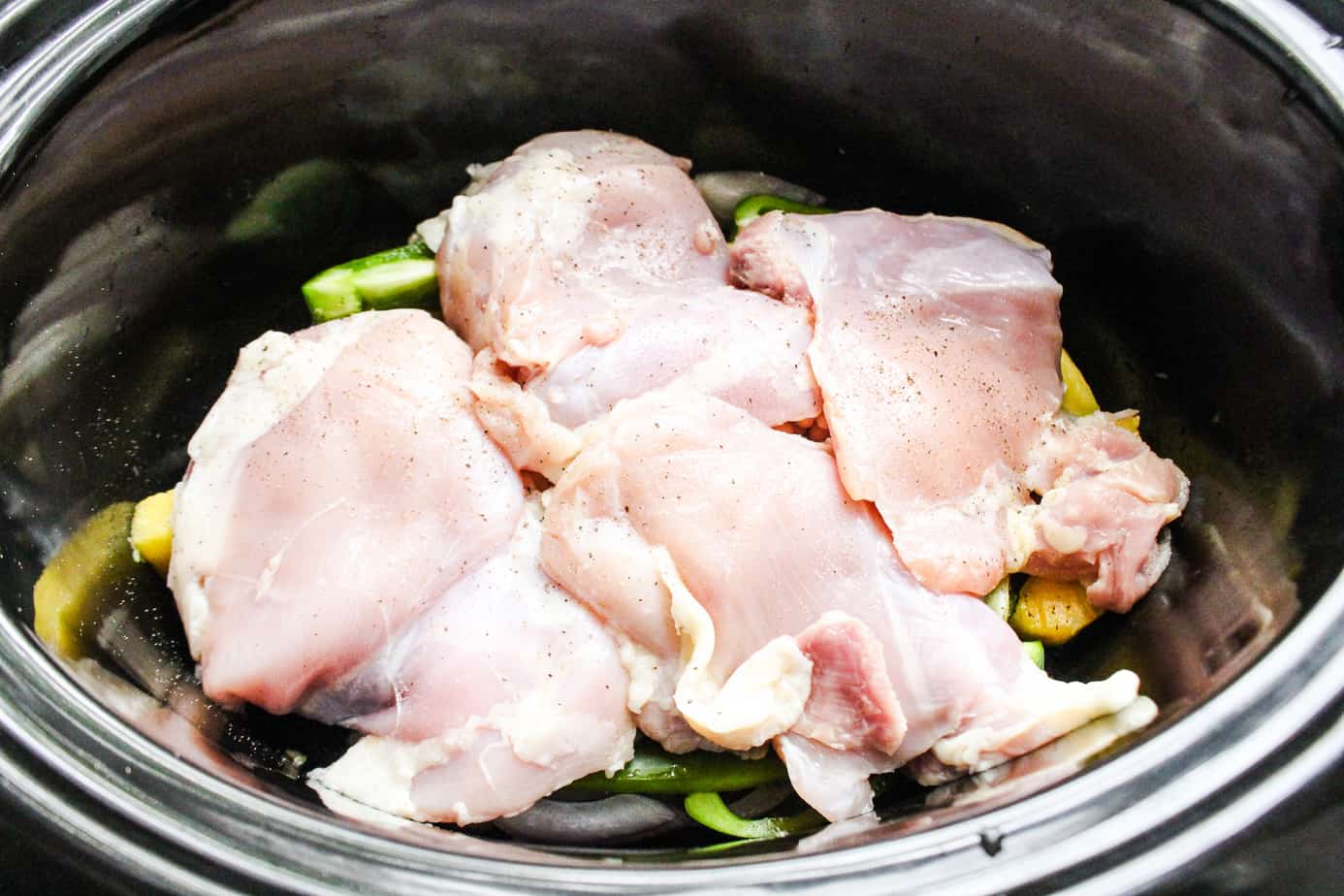 Slow cooker with pineapple, vegetables, white beans, and chicken thighs