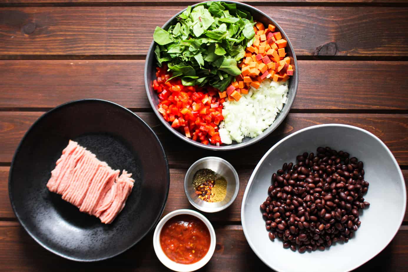 mise en place bowls of raw turkey, minced vegetables, black beans, spices, and salsa