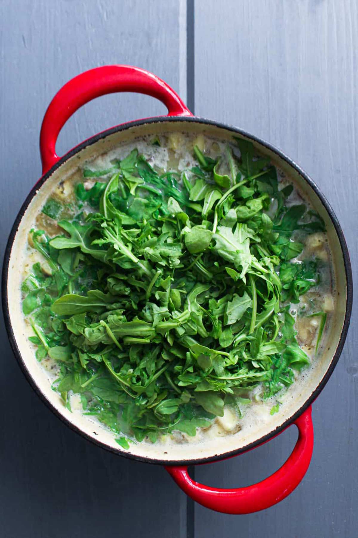 Arugula added to the pot of soup.