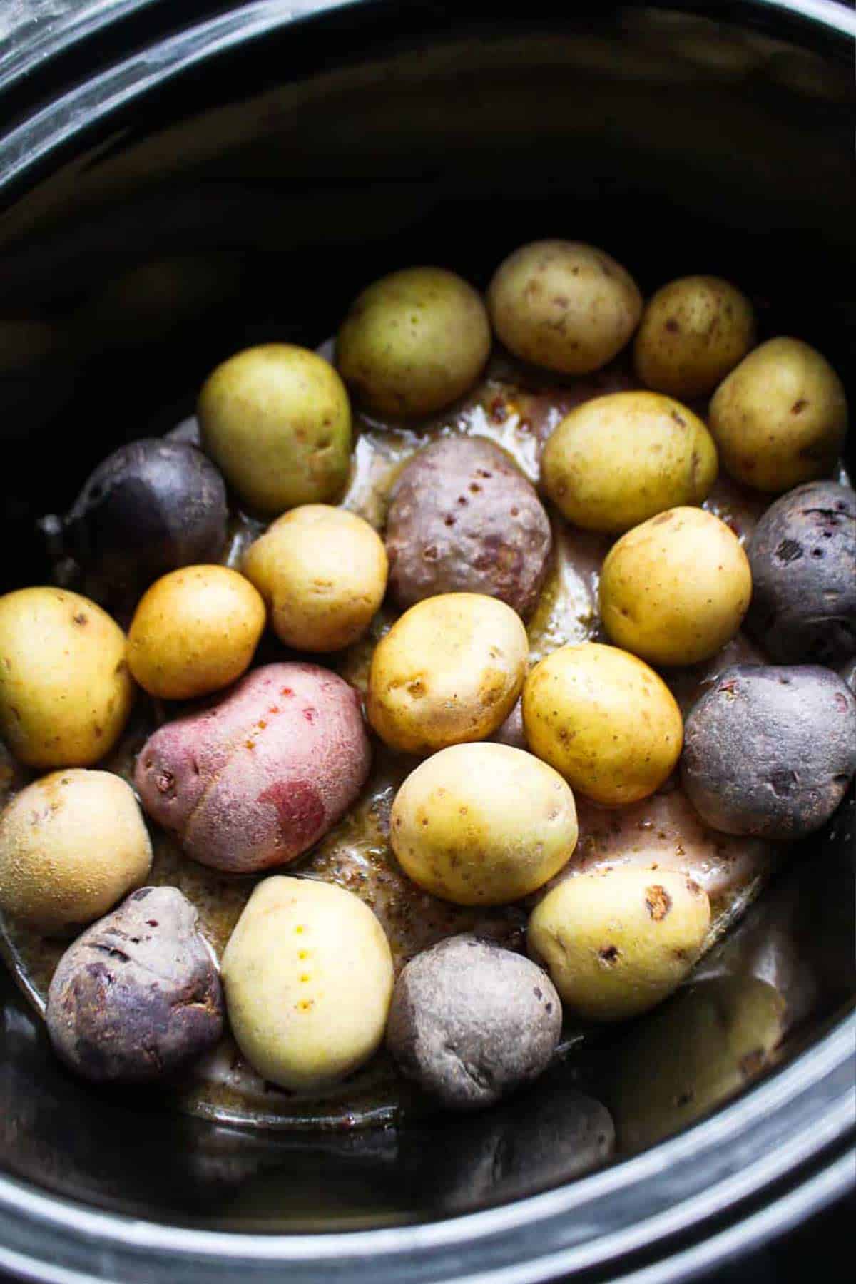 Baby potatoes on top of the pork chops in the slow cooker.