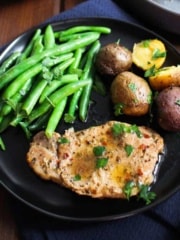 Slow cooker pork chops and potatoes on a plate with green beans.