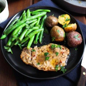 Slow cooker pork chops and potatoes on a plate with green beans.