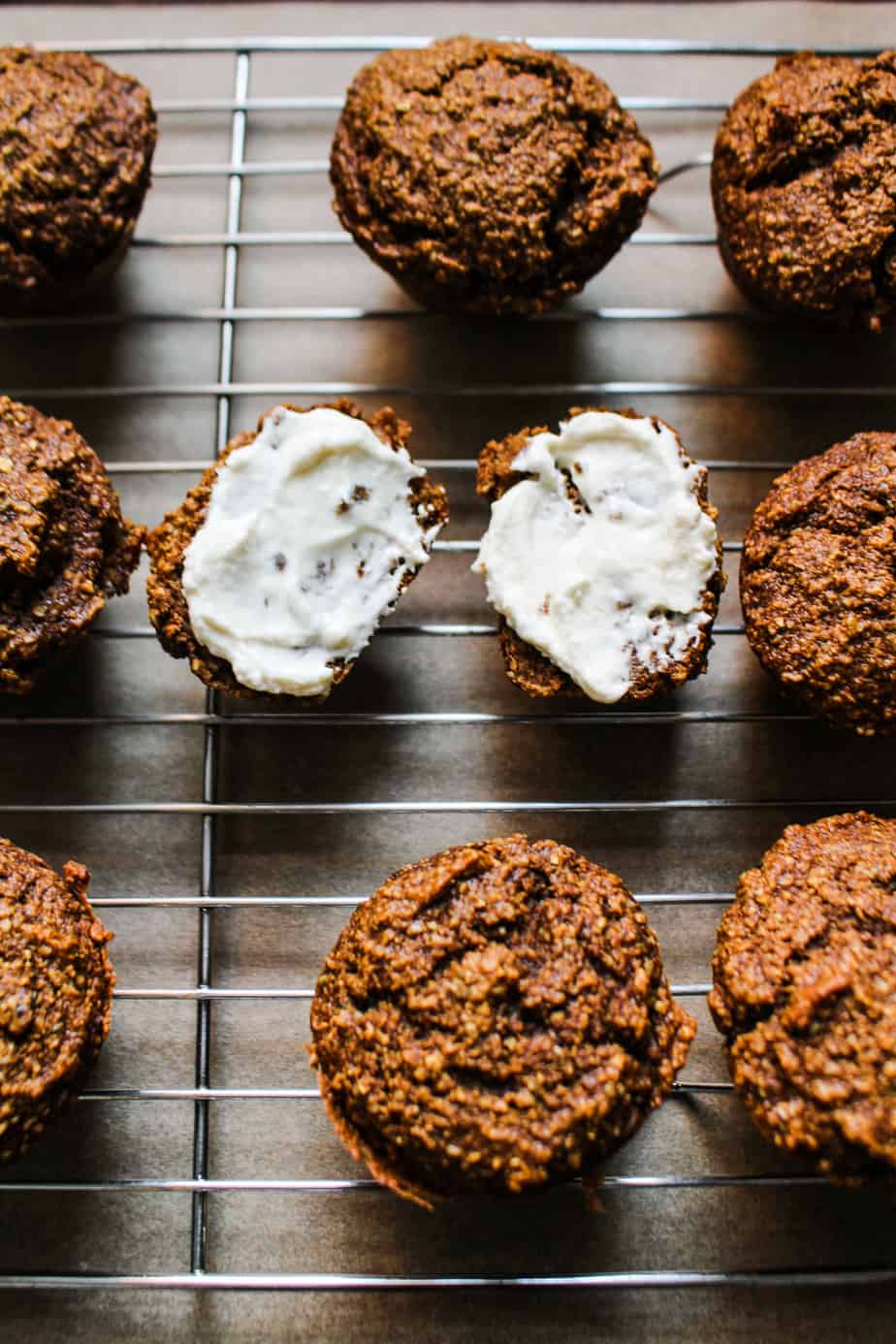 healthy gingerbread oat muffins with cream cheese topping on a wire cooling rack
