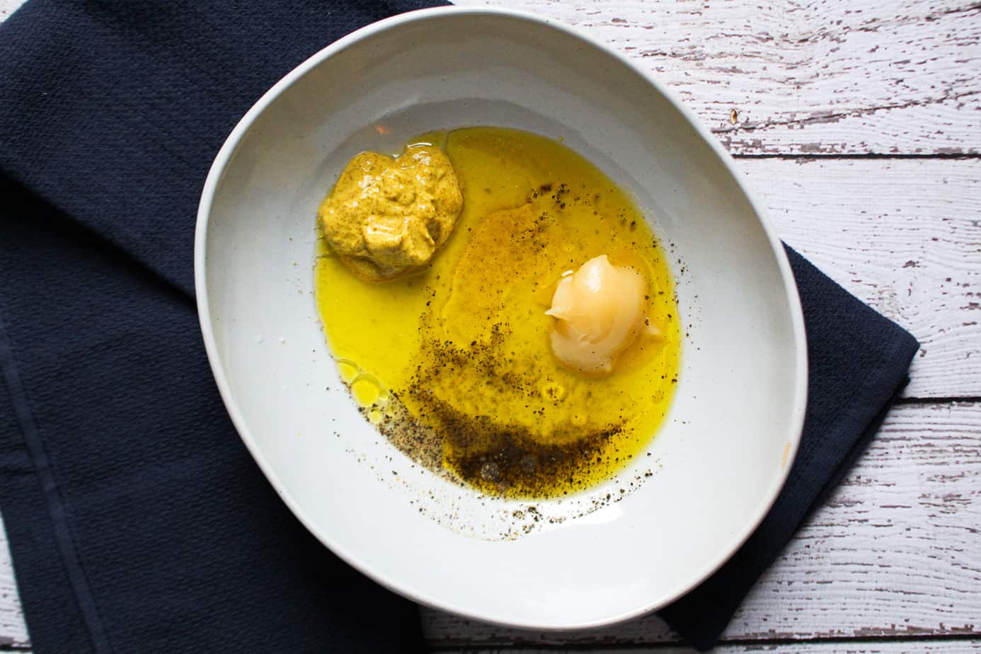 Bowl with olive oil, mustard, honey, vinegar, pepper, and turmeric