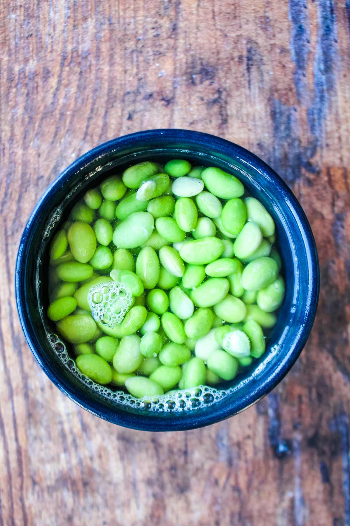 Bowl of edamame soaking in water.