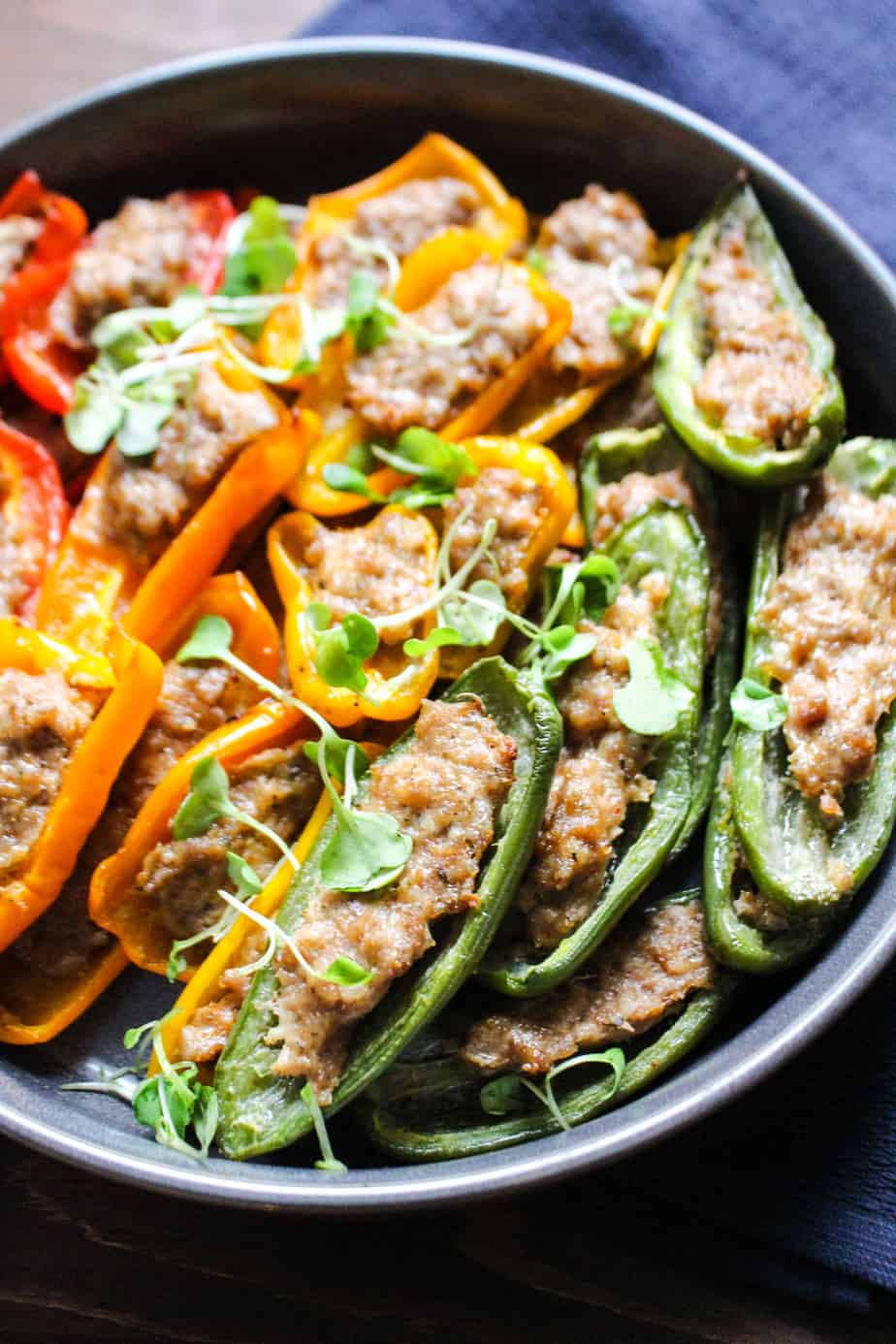 close up of large platter of sausage stuffed peppers of red, orange, yellow, and green.