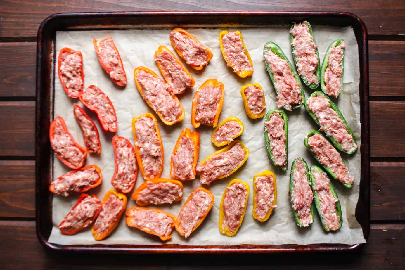 sheet pan with uncooked sausage stuffed mini peppers