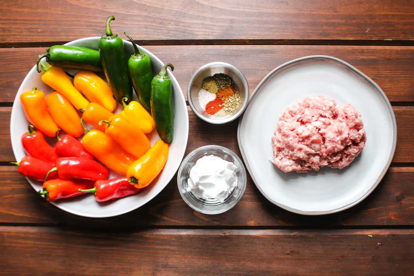 ingredients: a rainbow of mini peppers in red, orange, yellow, green, spices in a bowl, dairy free cream cheese, raw ground pork