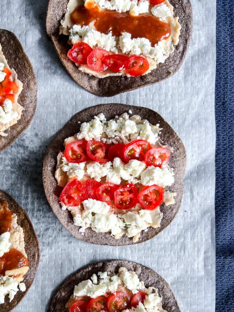 Blue corn tostadas are topped with white bean puree, with salsa, tomatoes, and crumbly cheese arranged to resemble the red and white stripes of the USA flag.