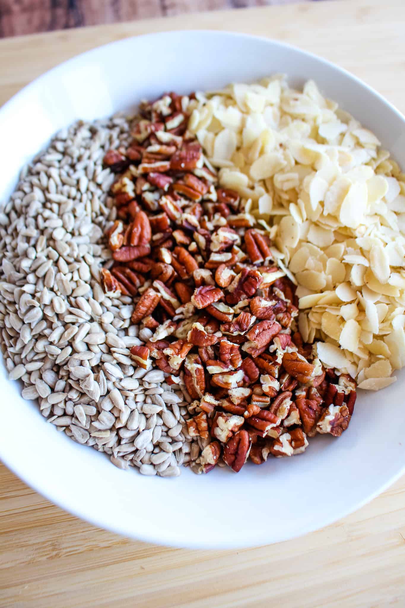 a bowl with seeds, nuts, and coconut shavings beside each other