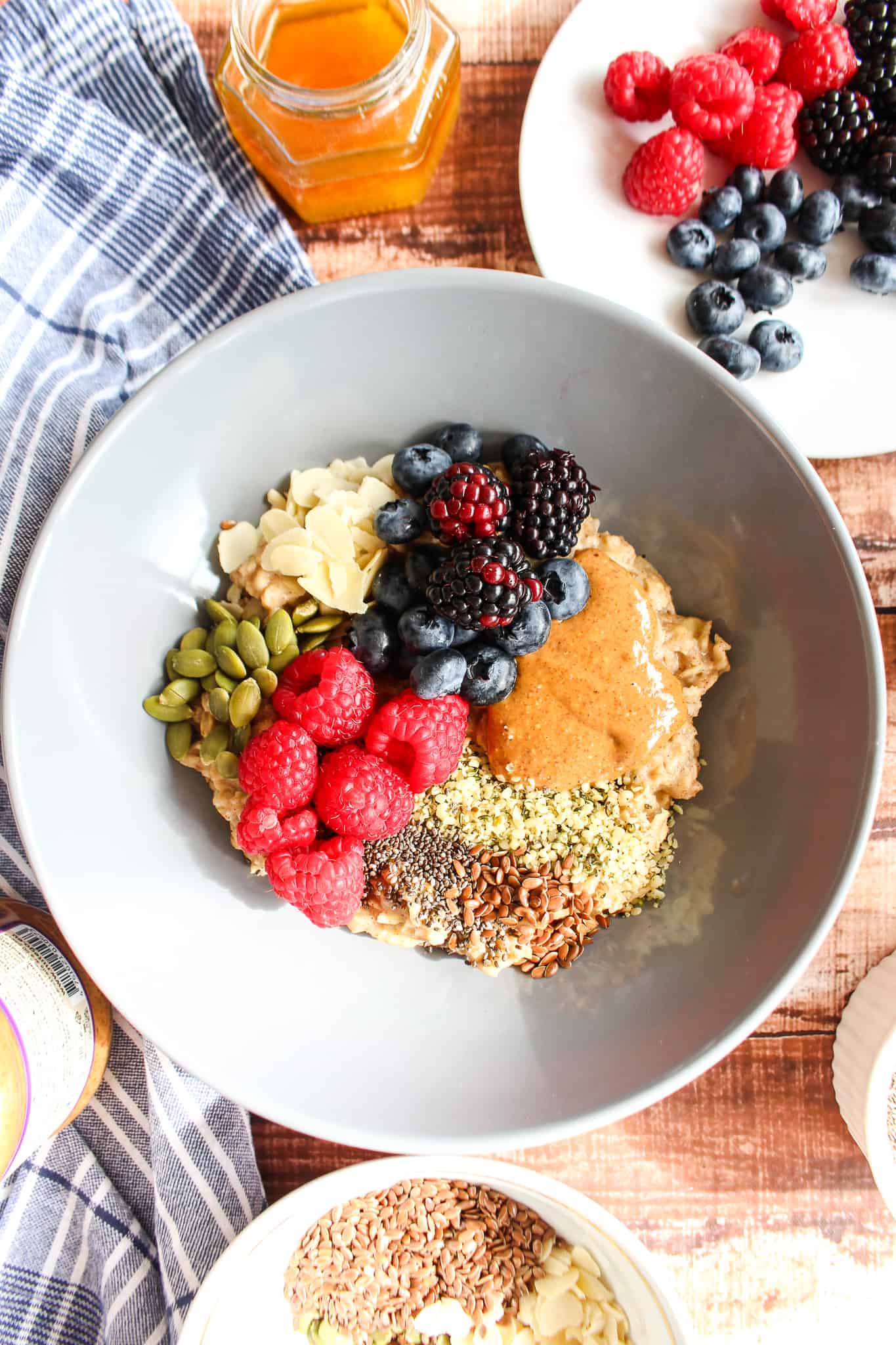 a bowl of oatmeal covered in blueberries, raspberries, seeds, coconut flakes, and other toppings