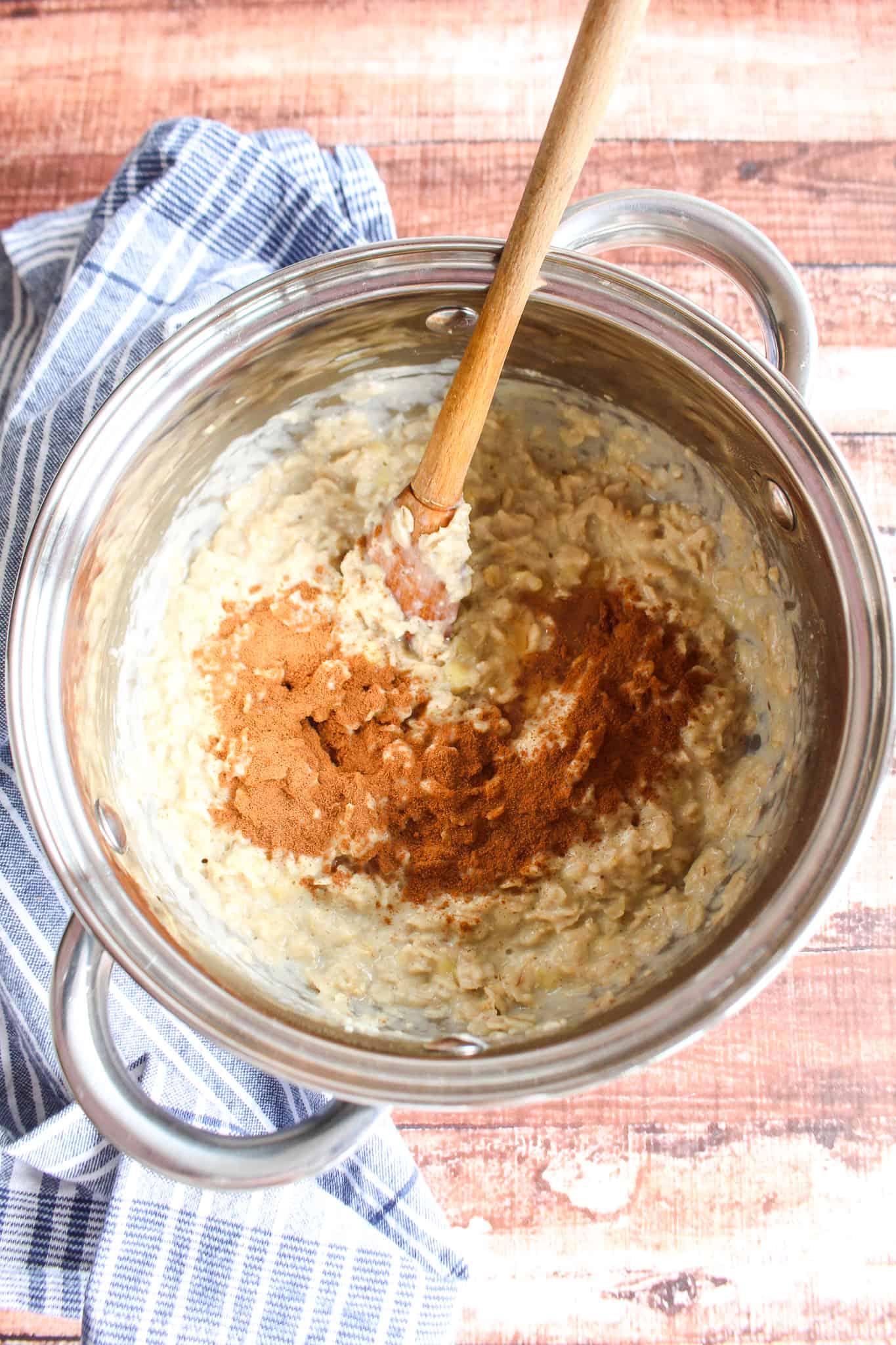 creamy oatmeal in a pot stirring in cinnamon