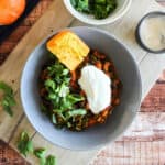 Pot of pumpkin turkey chili on the counter with a wooden spoon.