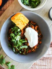 Pot of pumpkin turkey chili on the counter with a wooden spoon.