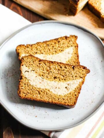 two slices of almond flour pumpkin bread with cheesecake filling on a plate