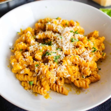 A bowl of pasta tossed with pumpkin pasta sauce.