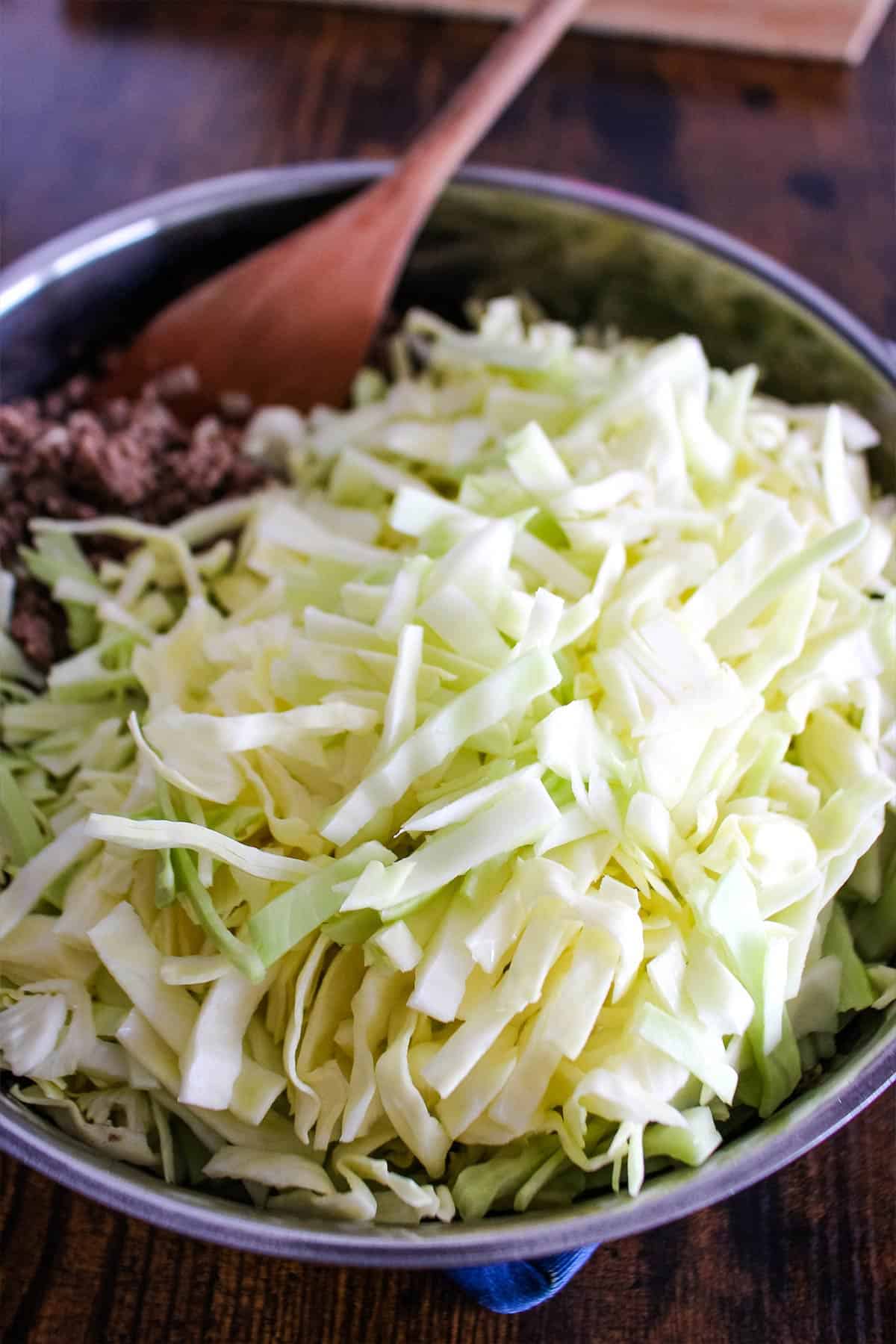 Adding the cabbage to the skillet.