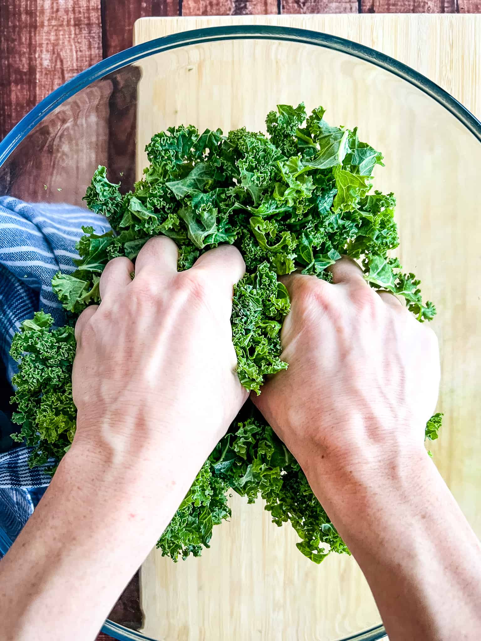 hand starting to massage kale