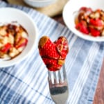 Fork holding a heart-shaped strawberry drizzled with chocolate and nut butter.