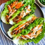 Pork lettuce wraps served up on a gray plate on the table.