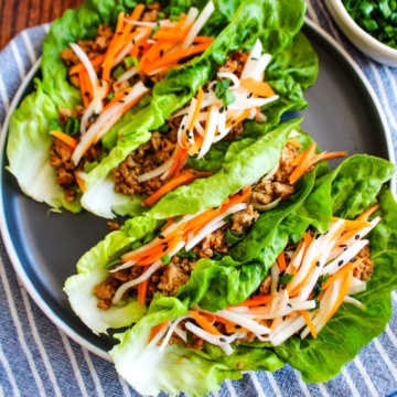 Pork lettuce wraps served up on a gray plate on the table.