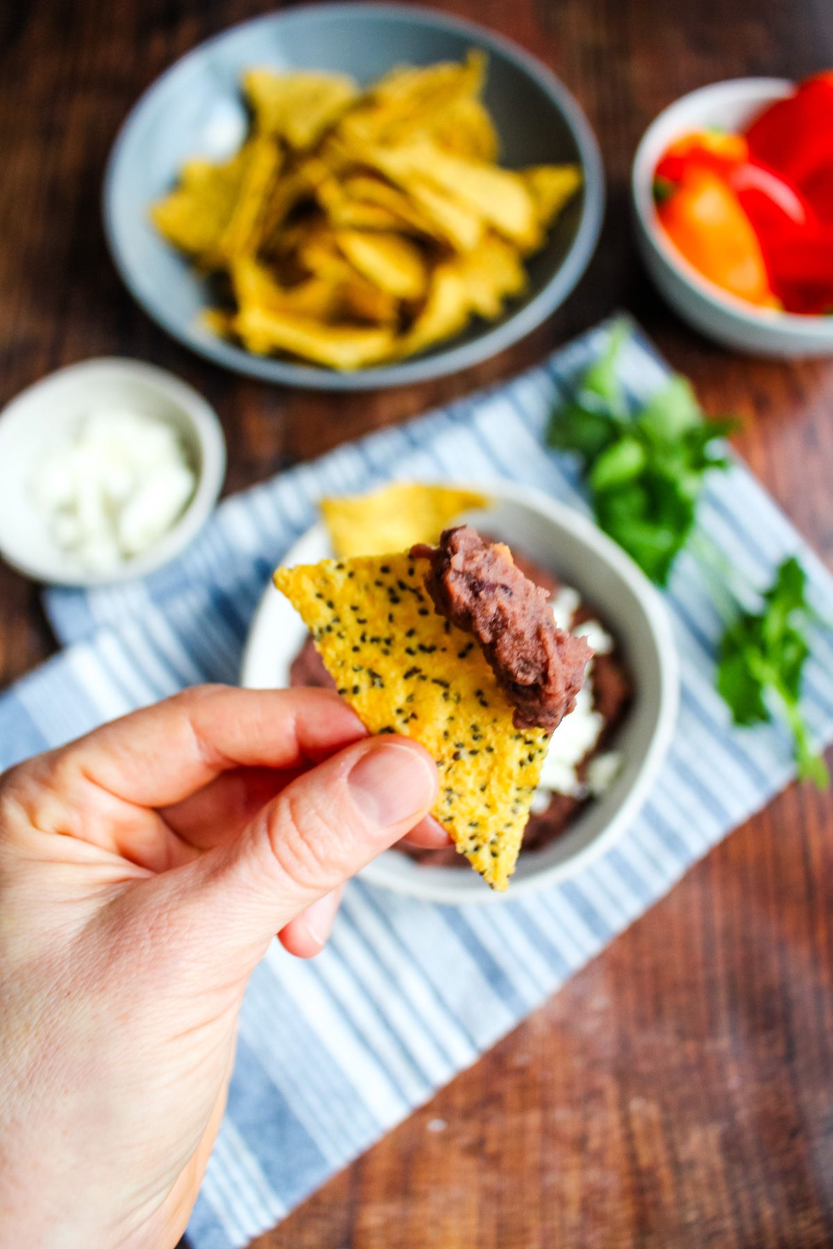 A scoop of black bean dip on a chip with a hand holding it.