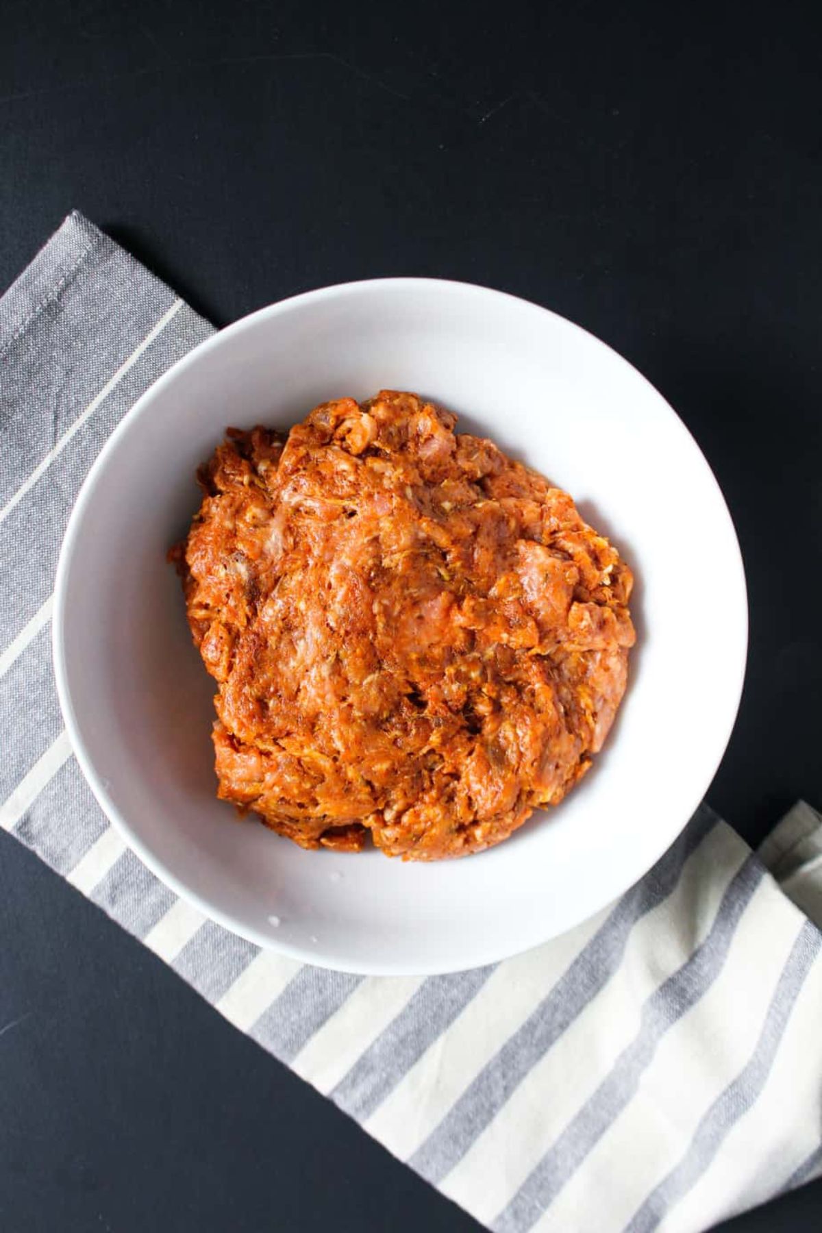 Bowl of raw meat with seasonings added.