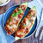 Ground turkey zucchini boats on a plate with a blue towel underneath.