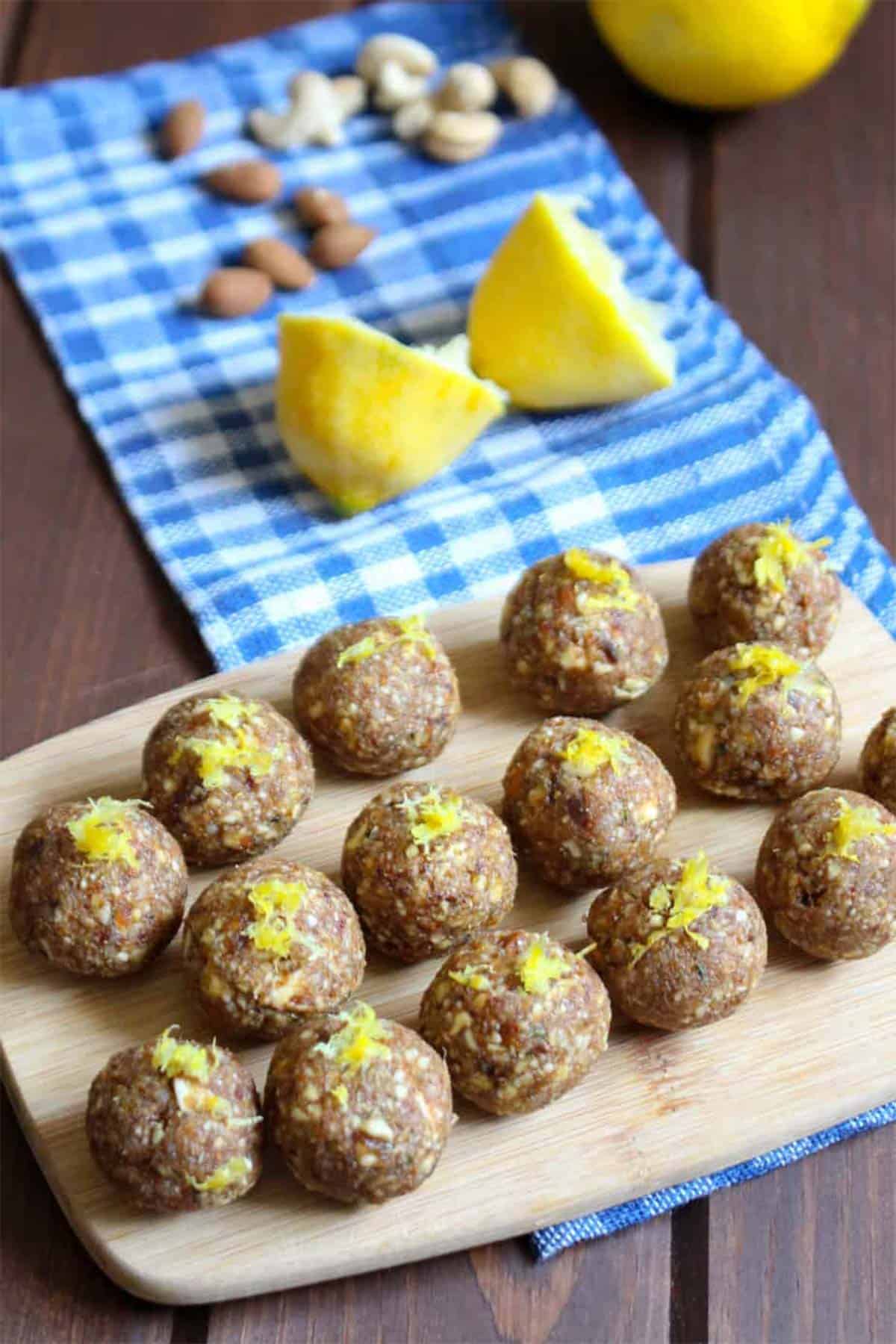Paleo energy bites with lemon, almond, cashews, and half the sugar on a cutting board.