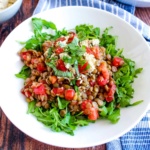 Mediterranean lentil salad served up in a white bowl.