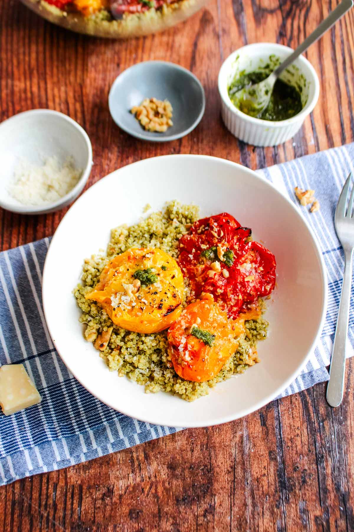 A white bowl on the table with pesto and quinoa with tomatoes.