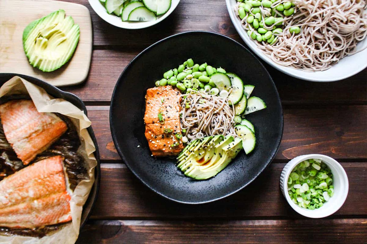 Salmon and soba noodles in a bowl with all the other ingredients added.